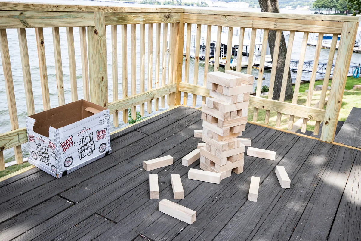 A stack of large wooden blocks set up for an outdoor game on the property, with a cardboard box nearby. The game is positioned to take advantage of the scenic outdoor setting, with plenty of space for family or friends to gather and play.