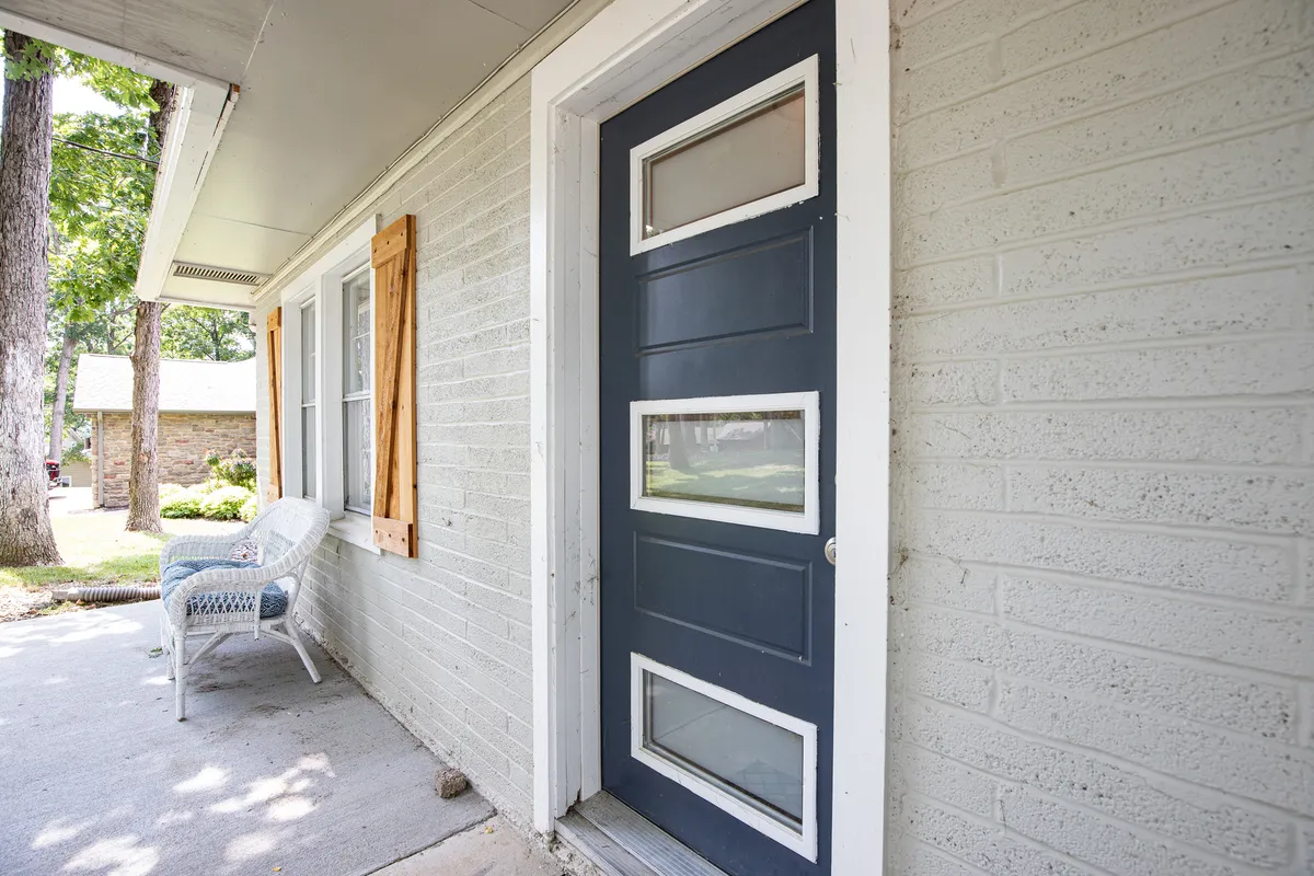 A close-up of the front door area with decorative shutters and a classic rocking chair set on the porch. The image conveys warmth and approachability, showcasing a space where guests can unwind and feel at home while enjoying the surrounding nature.
