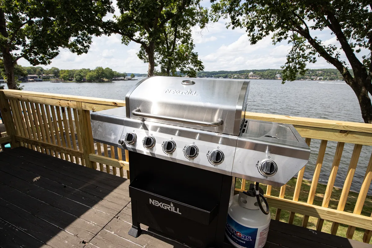 A wide deck equipped with a grill and dining area, framed by an expansive view of the lake. The setup suggests fun outdoor meals, gatherings, and the ease of stepping outside to enjoy the scenery with family and pets.